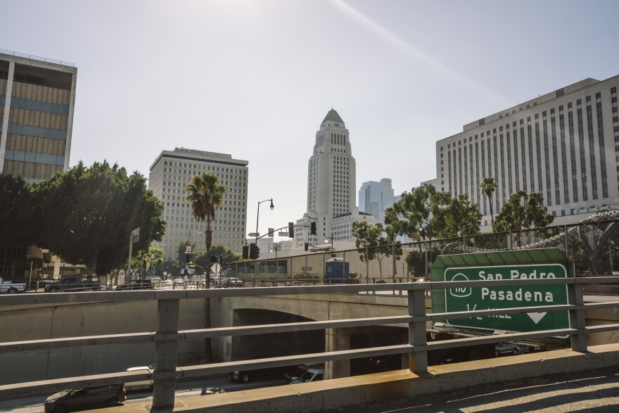 Los Angeles City Hall in the distance, looking across the 5 freeway. It's an art-deco style building with a pyramidal rooftop and white facade.
