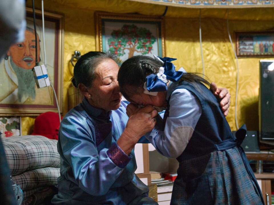 Oyutan's 8-year-old daughter, Mungunsaran Oyutan, is comforted by her grandmother, Tserenkhand Damba. The girl misses her mother, who took a factory job in Japan after struggling to find work in Ulaanbaatar.