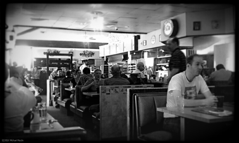 A black and white photo of diners at booths.