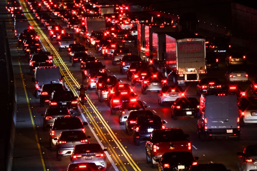 A freeway is full of cars with glowing red brake lights.