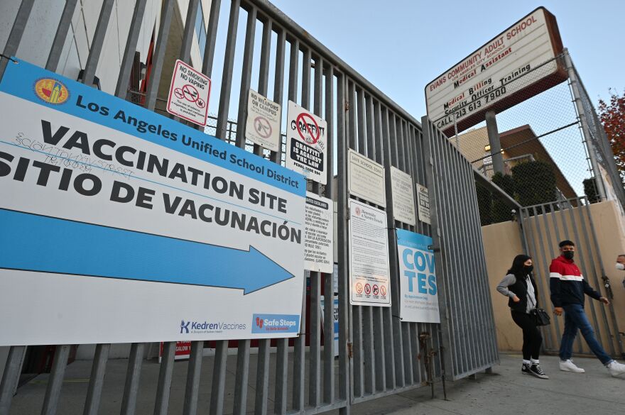 A sign hanging on metal fencing points the way to a vaccination site inside a LA Unified school campus.