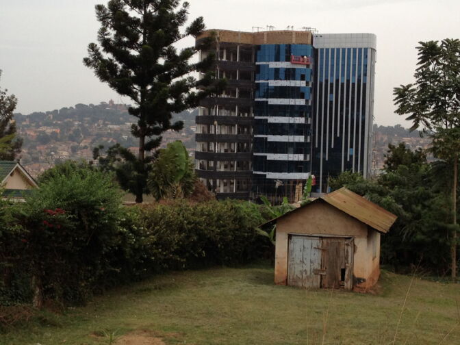 Contrasts in Kampala: a new glass and steel high-rise building under construction towers above a small rundown one-story structure.