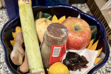 An apple, prunes, a guava and other items in a ceramic bowl.