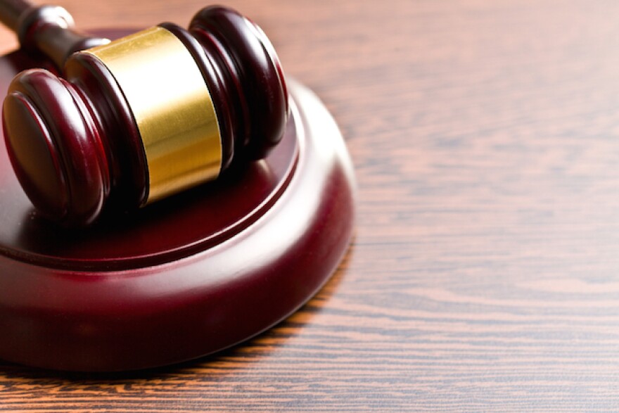 A woden gavel lays flat on a wood finish table.