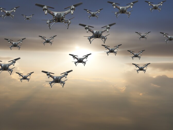 A flock of drones flying against a sunset. On Wednesday the Department of Transportation announced the launch of a pilot program that will lead to new regulations.