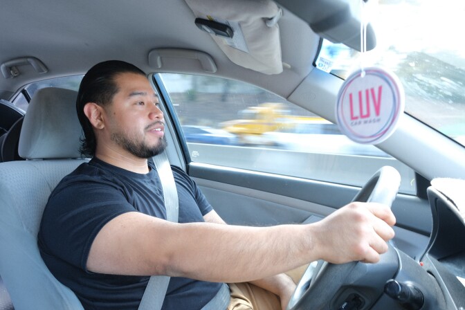 Luis Martinez, a man with medium skin tone, sits behind the wheel of his car while driving from Canoga Park to Santa Monica.
