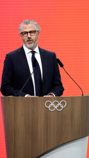 Casey Wasserman speaks at a podium.