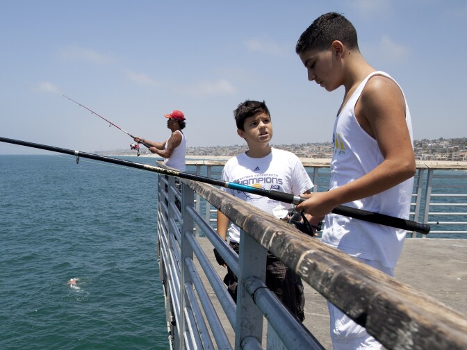 Paul Manasefi, 12, center, talks with John Zein, 13, as they fish on the Hermosa Beach Pier. Fishing is now prohibited at the Manhattan Beach Pier until Sept. 7 after a swimming was attacked by a juvenile great white shark caught on a fishing line.