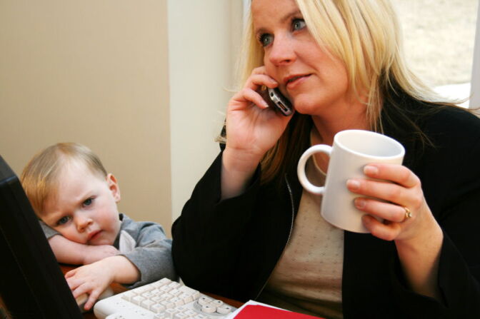 A mother talks on her cell phone, ignoring her young son.