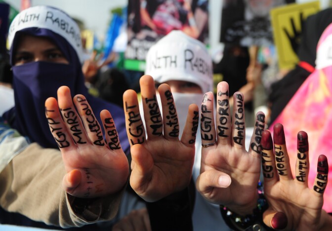 Islamic political party Jamaat-e-Islami (JI) activists gesture with painted fingers in support of ousted Egyptian president Mohamed Morsi in Karachi on August 20, 2013. 