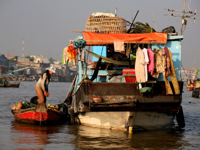 A woman stands in front of a houseboat moored near a floating market in Chau Doc, in southern Vietnam near the border with Cambodia.