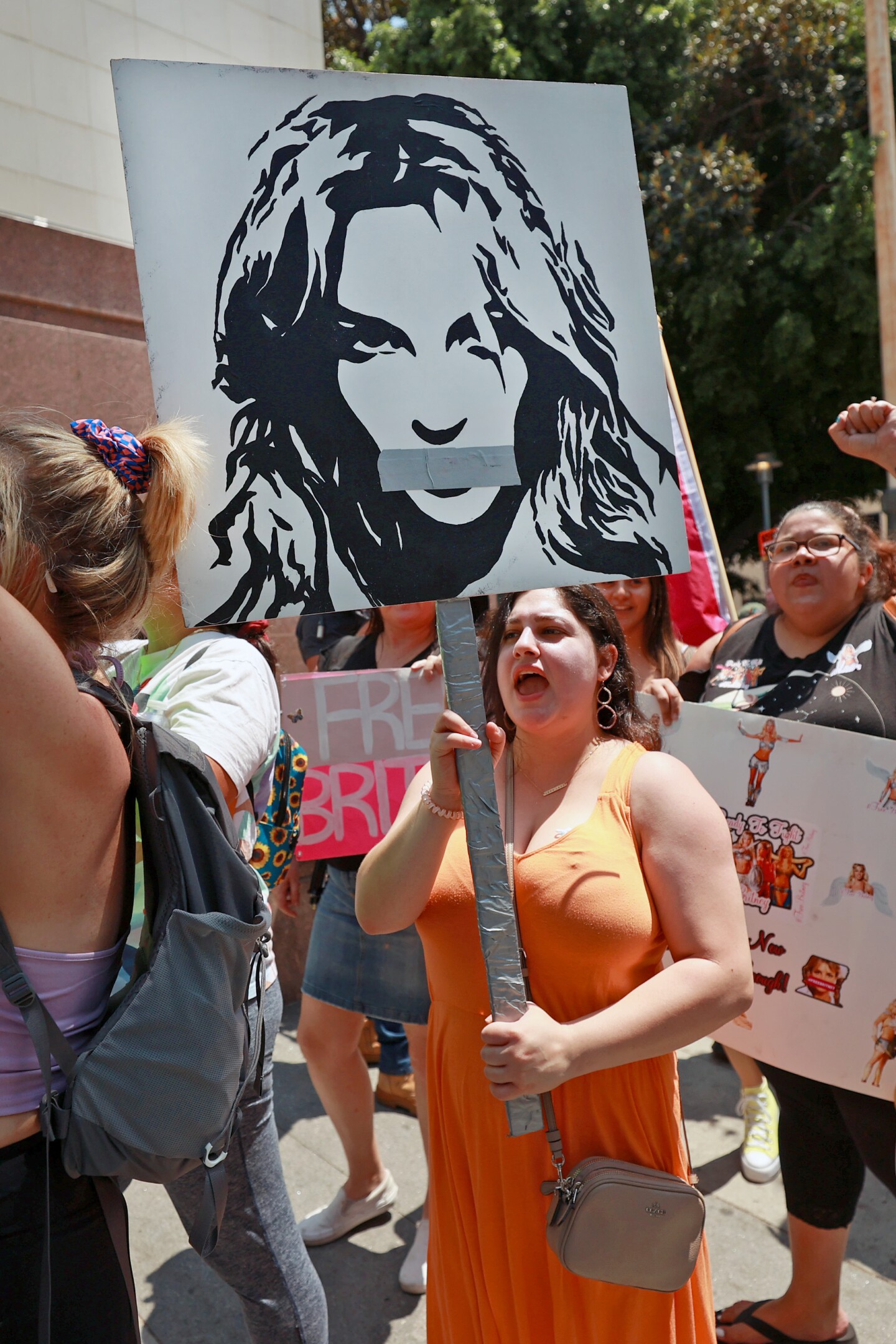 A protester holds a sign depicting Britney Spears with tape over her mouth.