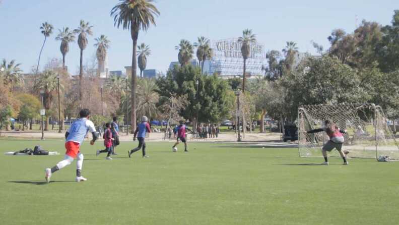 Six people play soccer in MacArthur Park.