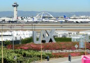 A traveler pulls his bags while walking past an LAX sign at Los Angeles International Airport as access roads were closed with flights delayed and cancelled after a gunman reportedly shot 3 people at a security checkpoint on November 1, 2013 in Los angeles, California. 