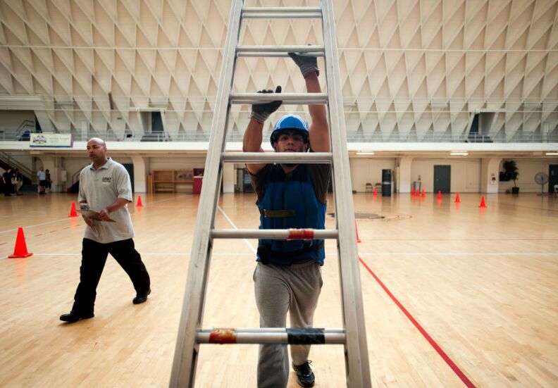 Firefighter Lamorris Wilcher, left, works with Noriega through the practice test. Noriega lifts a ladder against a wall, then extends it.