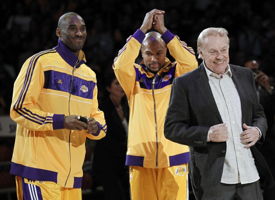 Los Angeles Laker owner Jerry Buss, right, walks out onto the court during the NBA championship ring ceremony as Kobe Bryant, left, and Derek Fisher look on before a basketball game against the Houston Rockets in Los Angeles, Tuesday, Oct. 26, 2010.