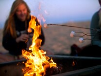 People gather at a fire pit near the Huntington Beach pier. 

