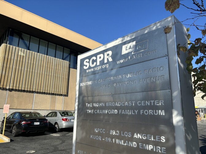 A metal sign outside a large beige building lists SCPR and LAist side-by-side.