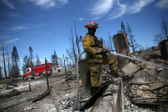 File: A firefighter cools off hot spots in the remains of a destroyed home on Sept. 16, 2014 in Weed, California.