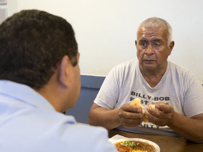 Rigoberto Bejarano (right), talks with intake coordinator Salvador Mendoza at Proyecto Pastoral on July 13, 2016. 
