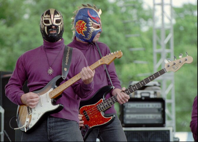 Eddy Angel, left, and Scott Esbeck of the Nashville-based band Los Straitjackets, wear Mexican wrestling masks while playing surf music at the Music Midtown festival in Atlanta.