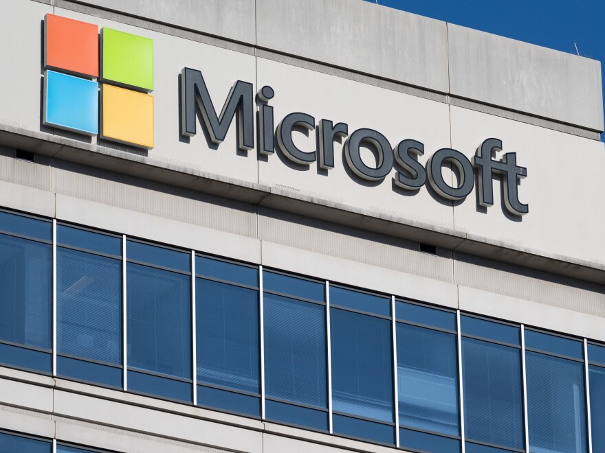 A grey building with a long row of windows has the word "Microsoft" written in black letters across the top.