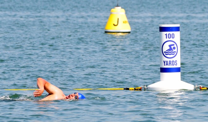 A man swims by one the newly installed distance buoys at Bayshore Aquatic Park in Long Beach.