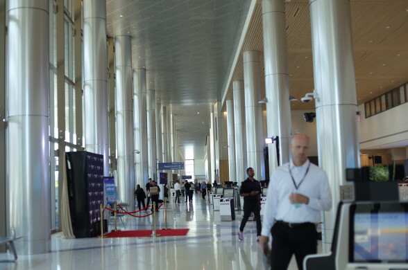 A wide view across the large terminal that looks down a row of tall white multiple columns. People are walking in the frame. The ceiling is high up.