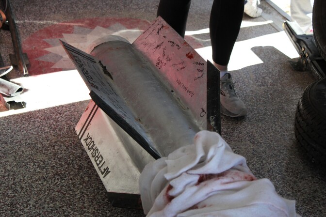 Part of a rocket made of gray metal. The metal is covered with signatures on the sides.