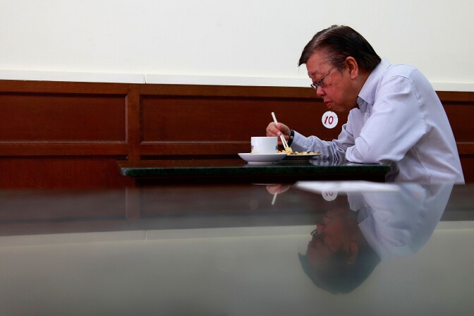 SINGAPORE - APRIL 01:  A man has his breakfast inside a coffeeshop located in a shophouse on Purvis Street on April 1, 2013 in Singapore. A shophouse is a vernacular architectural building type that is commonly seen in areas such as urban Southeast Asia. Shophouses are mostly two or three stories high, with a shop on the ground floor for mercantile activity and a residence above the shop. This pre-industrial form of urban units, prevalent in 19th and early 20th century Southeast Asian towns, cities and commercial centres, literally housed everything from work to home. Today, these buildings are recognised for their significance not only as an architectural heritage but more importantly as a reflection of the island's societal history and development.  (Photo by Nicky Loh/Getty Images)