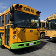 A yellow bus with a green fender. Black letters above the windshield read "SCHOOL BUS." 