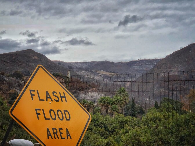 File: In this photo provided by Santa Barbara County Fire Department, a flash flood area sign is posted, as evacuations have been issued for several fire-ravaged communities in Santa Barbara, Monday, Jan. 8, 2018.