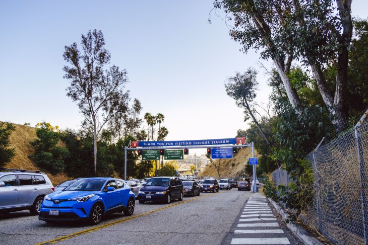 Cars are lined up in heavy traffice to enter Dodget Stadium, while the pedestrian walkway is completely empty.