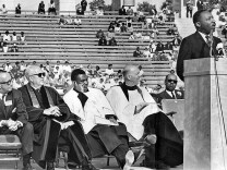 The Rev. John Burt, seated at far right, listens as Martin Luther King Jr. addresses 15,000 people at the Coliseum during an interfaith rally in 1964. Burt helped organize massive civil rights rallies in Los Angeles. -- PHOTOGRAPHER: Los Angeles Times

 1964 staff file photo of Martin Luther King speaking at civil rights rally. From left in front row is entertainer Walter O'Keefe, the Rev. Myron C. Cole, The Rev. Joseph Francis and the Rev. John H. Burt. 