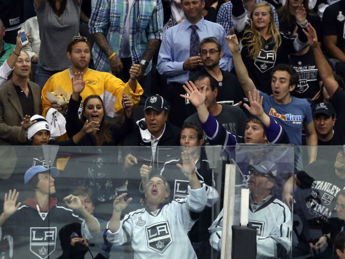 Hockey fans look to catch a puck going over the glass during Game 3 of the 2012 Stanley Cup Final between the New Jersey Devils and the Los Angeles Kings at Staples Center on June 4, 2012 in L.A., Calif.
