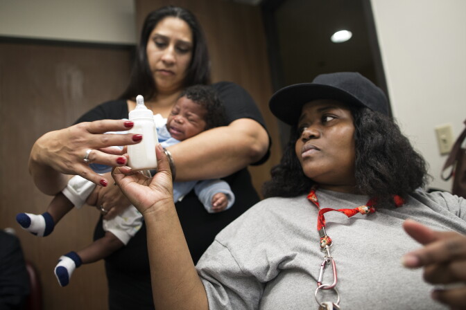Mother Tamika Rosser hands a bottle to Health Educator Cecie Trujillo for 2-month-old Tray'von Lynn. Great Beginnings for Black Babies also provides child care during the class.