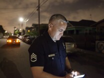 Los Angeles Police Sergeant Raul Jovel enters data in a field report after making a stop on E. 28th St. to check on some metro officers who were doing a search at a home on Tuesday, May 12, 2015 in Los Angeles, Calif. The search later turned up methamphetamines packaged for sale, a scale,  and ammunition including .380 auto,  .40 caliber, .357 magnum and rifle rounds, according to metro officers who were at the scene. 