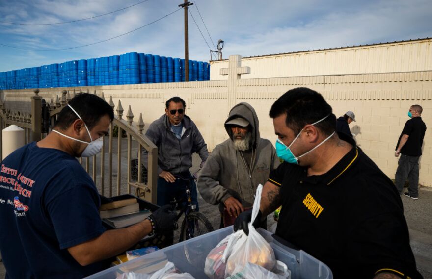 VENTURA, CA - MARCH 31: Ventura County Rescue Mission workers hand out food packages to the homeless on March 31, 2020 in Ventura, California. This faith-based mission usually allows people to come in and eat but due to the COVID-19 crisis, food is now handed out in packages by servers with masks and gloves. There is also the option of a bible. This mission recently had a number of people removed by the Sherrif's Department as a result of a suspected coronavirus case. Homeless people who are suspected of possibly having the virus or having been around someone who does are being quarantined in two local hotels taken over by the Public Health service for the next few weeks. (Photo by Brent Stirton/Getty Images)