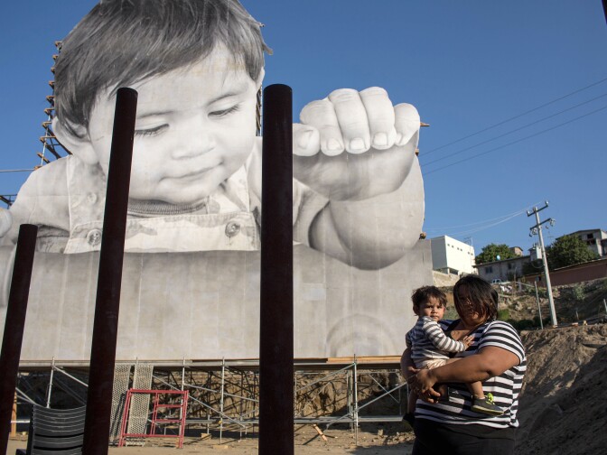 Lissy and her son Enrique Achondo, who was pictured by French artist JR for his artwork, poses for a picture on the Mexican side of the US - Mexico border where the giant print of Enrique has been installed in Tecate, Baja California, Mexico on September 6, 2017.