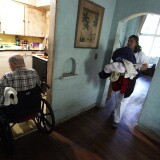 MIAMI - DECEMBER 14:  United HomeCare Services home health aide Wendys Cerrato carries bedding to the washing machine as she helps Robert Granville in his home on December 14, 2009 in Miami, Florida. The U.S. Senate continues to debate the need for the Community Living Assistance Services and Supports (CLASS) Act in the health care reform bill, which would provide a government-sponsored basic cash benefit to those needing long-term care services at home, in assisted living, or in a nursing facility. Without the help of United HomeCare Services Robert would be unable to continue to live on his own since he has limited mobility.  (Photo by Joe Raedle/Getty Images) *** Local Caption *** Robert Granville;Wendys Cerrato