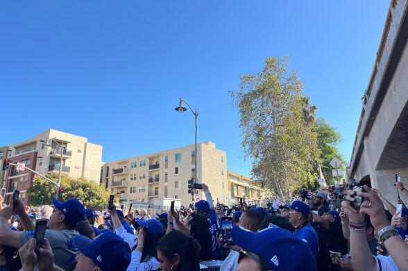 A crowd of people, many wearing blue hats, holding their phones to take photos.