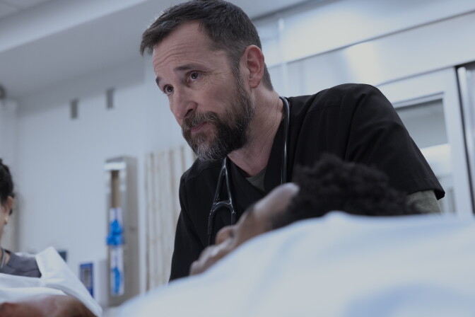 A photo still from a TV show featuring a white man in a hospital setting.