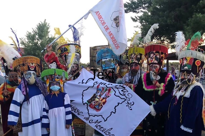 A group of dancers in traditional dress for a Dia de los Muertos celebration.