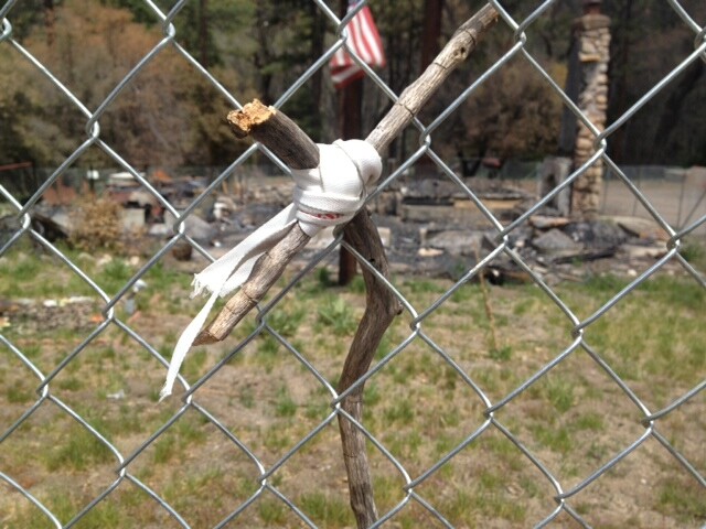 A cross made of twigs and shoelaces was left at the fence that surrounds what remains of the cabin that burned down with Christopher Dorner inside near Big Bear.