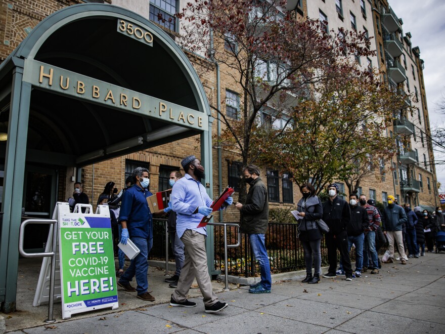 People line up outside a free COVID-19 vaccination site that opened Friday in Washington, D.C. The local health department is stepping up vaccination and booster shots as more cases of the omicron variant are being identified in the U.S.