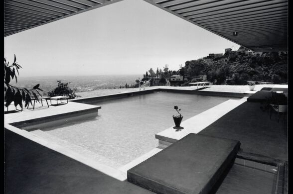 A black and white photo of an outdoor swimming pool of a mid-century modern home overlooking the city of Los Angeles.