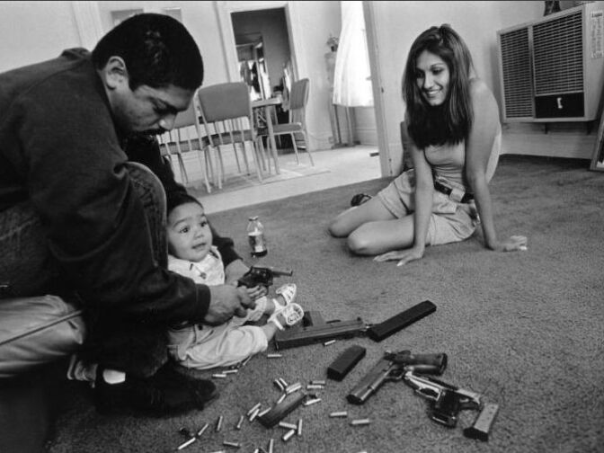 A father teaches his daughter how to hold a .32 caliber pistol the morning after a rival gang tried to shoot up his home and family for the fourth time.