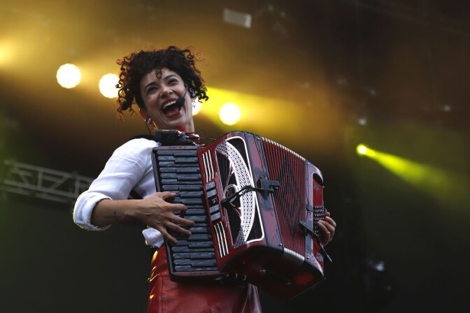 An image of singer Flor Amargo, who is playing a red accordion while yellow lights illuminate the stage.