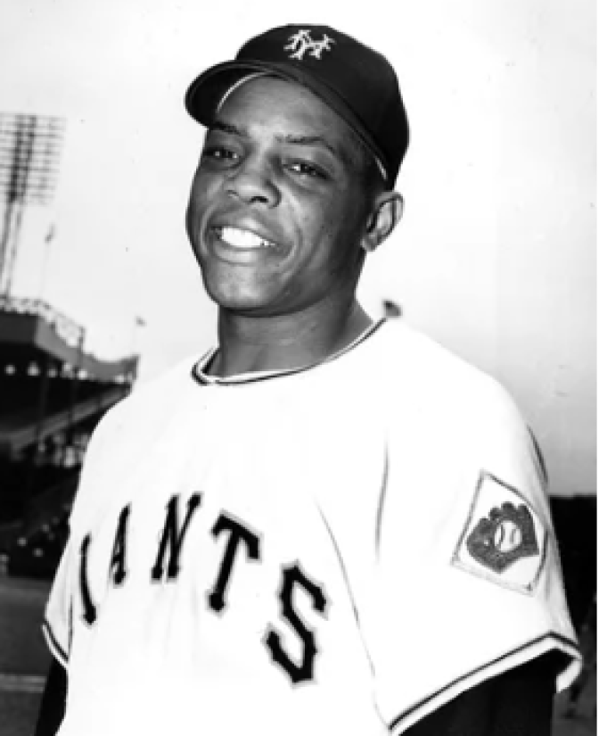A man is wearing a Giants jersey and baseball cap in a black and white photo. 