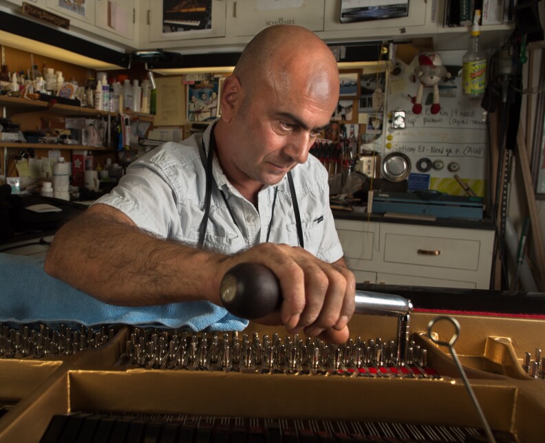 Steve Bagmanyan, a piano repair technician tunes a Steinway and Sons piano at the LAUSD Music Repair Shop.
